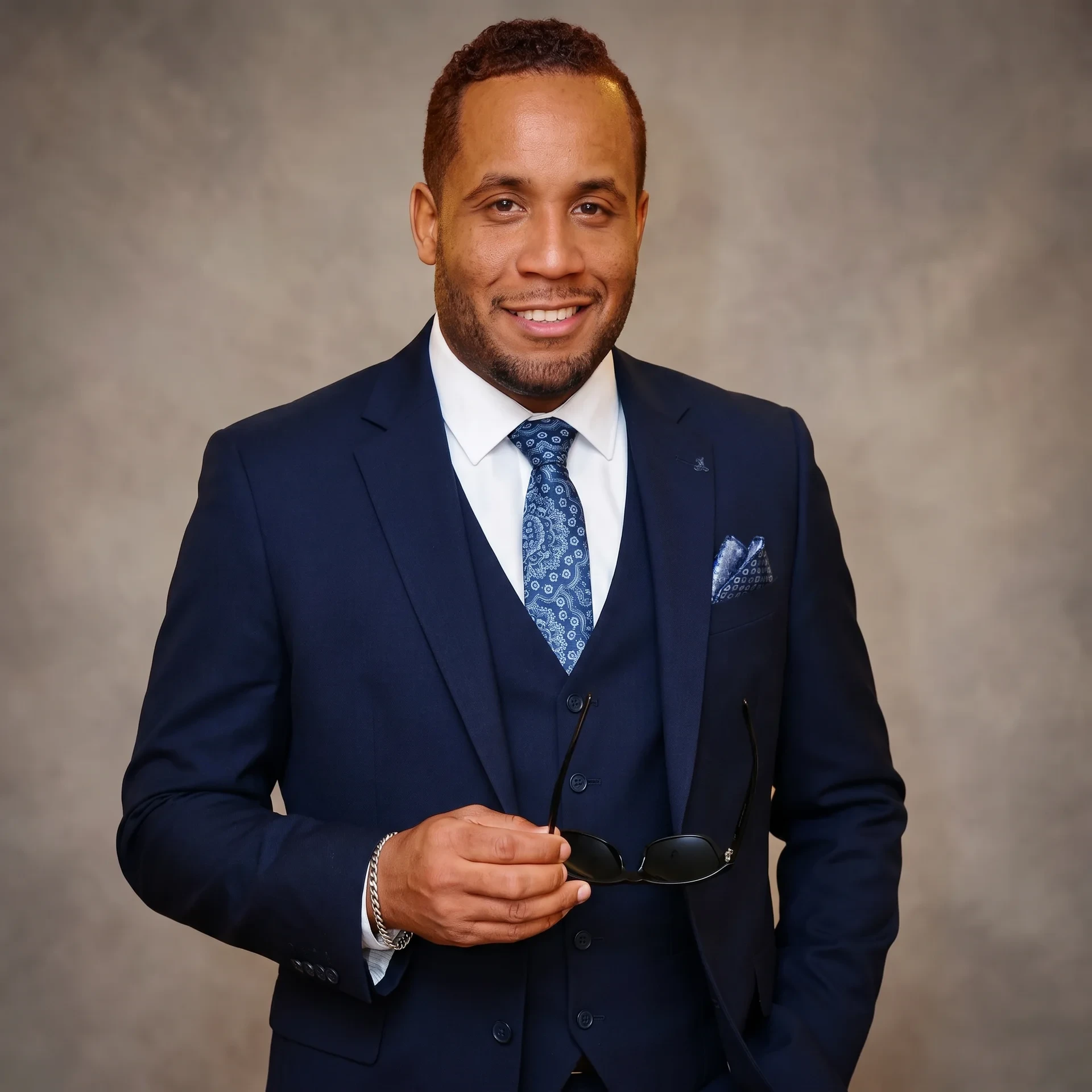 JR, broker and CEO of Rubirosa International Realty, in a navy three-piece suit